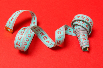 Perspective view of spiral measuring tape on red background. Close up of slimming concept
