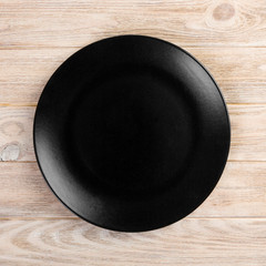 Round plate on table. black dish on wooden background. copy space