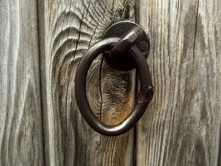 The photo of an old forged ring on a wooden door.