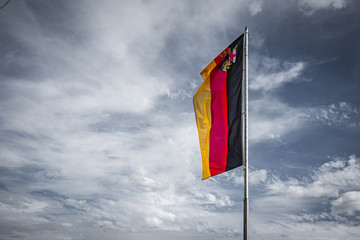 Deutschland Flagge Rheinland-Pfalz an Fahnenmast vor dramatischem Himmel mit Wolken