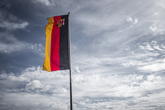 Deutschland Flagge Rheinland-Pfalz an Fahnenmast vor dramatischem Himmel mit Wolken