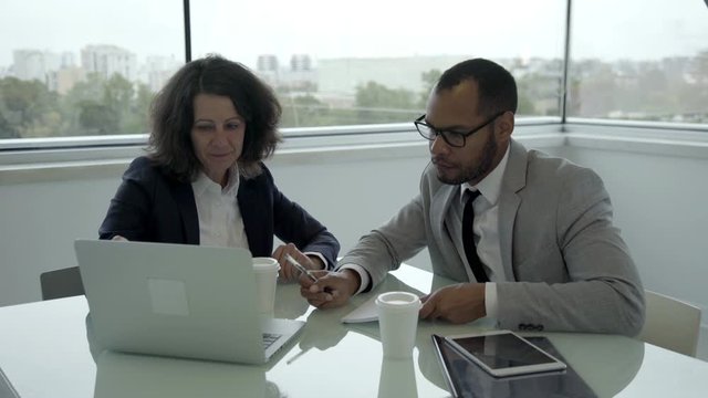Smiling manager talking with client in office. Smiling office employees working with laptop. Business meeting concept