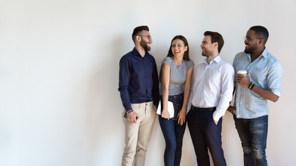 Cheerful multiracial professional business people laughing standing near wall