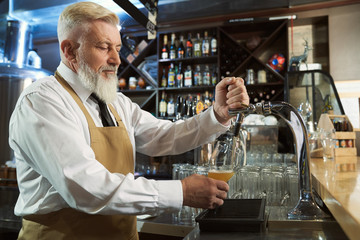 Man in process of pouring light beer in glass from beer tap