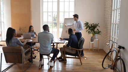 Businessman speaker giving presentation to multiracial business people in office