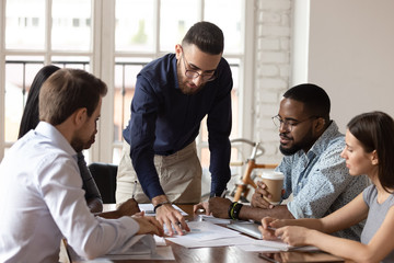 Focused team listen male boss review work result at meeting