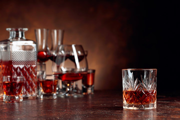 Set of strong alcoholic drinks in glasses on a brown background.