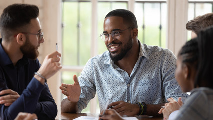 Smiling male african leader talking to colleagues at office briefing