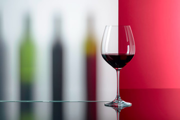 Bottles and glass of red wine on a black reflective background.