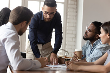 Serious male boss analyzing financial report at group corporate briefing