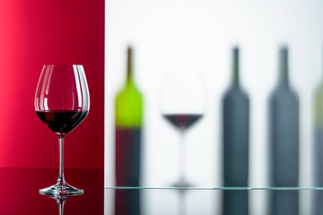 Bottles and glasses of red wine on a black reflective background.