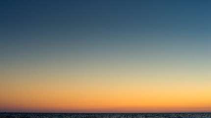 Relaxing beach background with clear sunset sky in the horizon with the sea