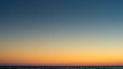 Fototapeten Entspannender Strandhintergrund mit klarem Sonnenunterganghimmel am Horizont mit dem Meer © Iaroslav