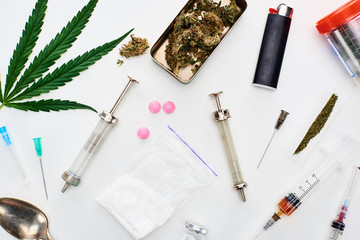 top view of marijuana buds, cannabis leaf, heroin, pills and syringes on white background