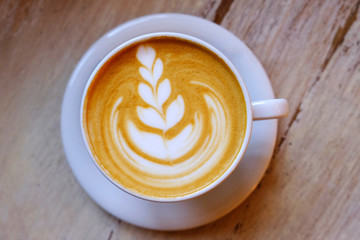A cup of coffee cappuccino with latte art on wooden background.