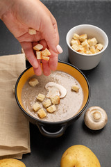 Woman adding croutons to mushroom cream soup