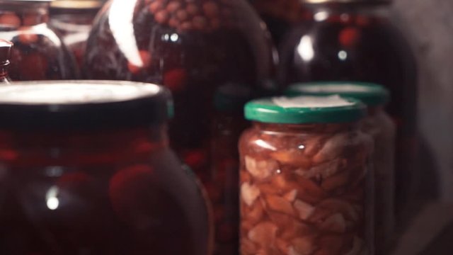 The old woman's hand takes a can of compote from the shel. Canned compotes are in the basement. Saving in glass jars. Preparation for organic beverages in winter