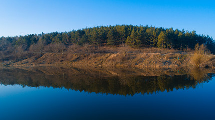 A beautiful forest reflecting in a large lake before it.