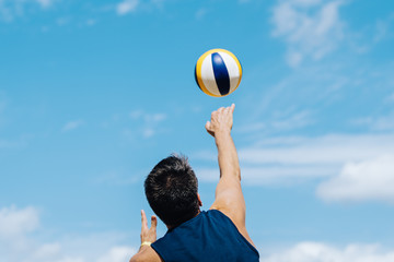 Man playing volleyball in the summertime after corona crisis surcharge blue sky playing with ball fitness
