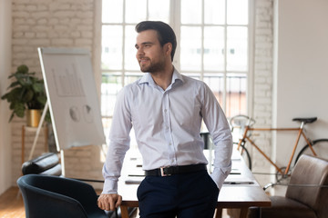 Successful happy businessman standing in office dreaming of new goals