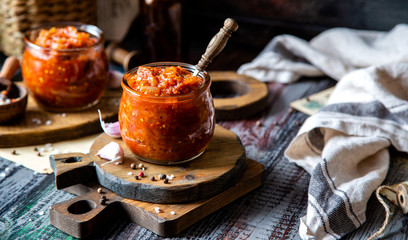 two glass jars with home made red vegetable caviar, ratatouille, ragout on wooden brown boards