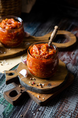 two glass jars with home made red vegetable caviar, ratatouille, ragout on wooden brown boards