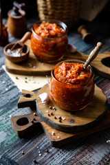 two glass jars with home made red vegetable caviar, ratatouille, ragout on wooden brown boards