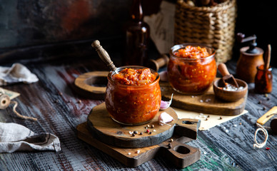 two glass jars with home made red vegetable caviar, ratatouille, ragout on wooden brown boards