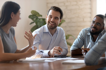 Happy business woman telling joke to male colleagues at meeting