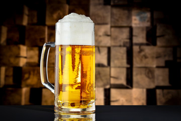 A pint of beer on the black table and wooden wall background.