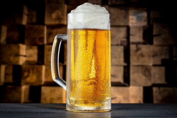 A pint of beer on the black table and wooden wall background.
