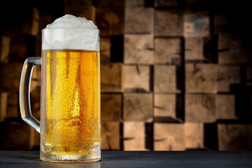 A pint of beer on the black table and wooden wall background.