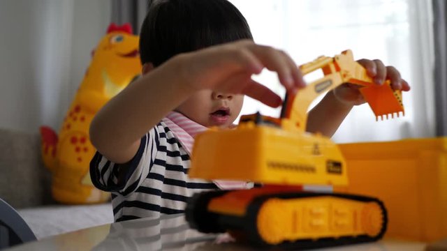 cute asian child playing truck construction toy in home