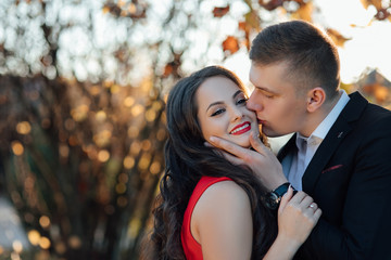 Couple in love in autumn park, enjoying a beautiful autumn day. Man kissing a woman in a forehead. True love among lovers. Sincere emotions and love on the planet. 