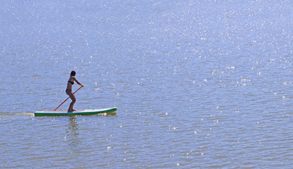 woman in a bikini doing stand-up paddling on a lake