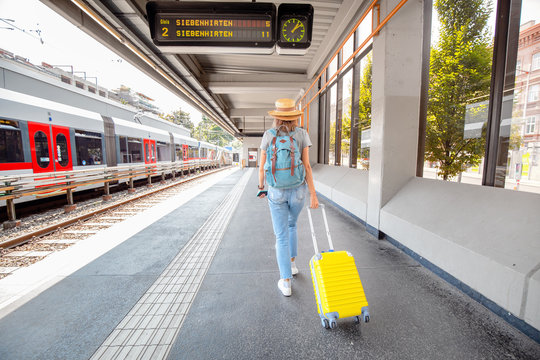 woman with suitcase walking at the railway station. Summer vacation and transportation concept