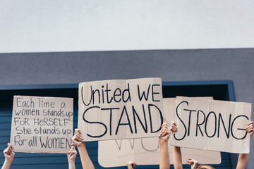 cropped view of women holding placards with feminist slogans on street