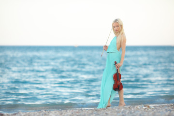 Girl on the beach plays the violin.
