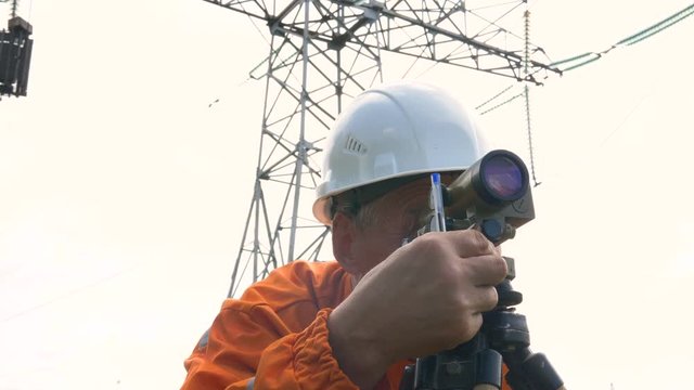 senior surveyor adjusts dumpy level rotating knob and writes
