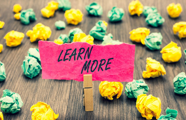 Writing note showing Learn More. Business photo showcasing Deepen knowledge of the thing you want to do or new skill Clothespin holding pink note paper crumpled papers several tries