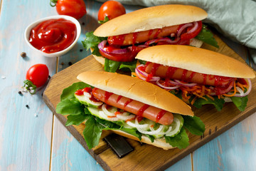 Traditional american fast food. Barbecue grilled Hot dog with fresh vegetables on wooden table with copy space.