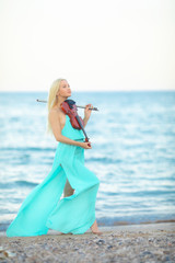 Girl on the beach plays the violin.