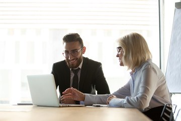 Mature businesswoman mentor helping new employee with corporate software