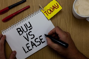 Handwriting text writing Buy Vs Lease. Concept meaning Own something versus borrow it Advantages Disadvantages Man holding marker notebook clothespin reminder wooden table cup coffee