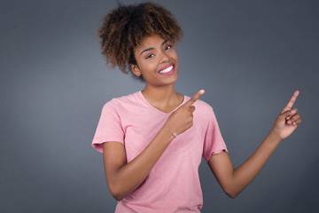 Pretty young brunette woman with positive expression, dressed casually, indicates with fore finger...