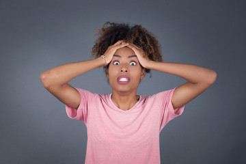 Horrible, stress, shock. Portrait of young African American woman clasping head in hands. Human emotions, facial expression concept. Trendy colors.