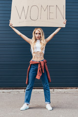 full length view of feminist holding placard with word women on street