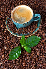 Food background with black roasted coffee beans and mug with coffee