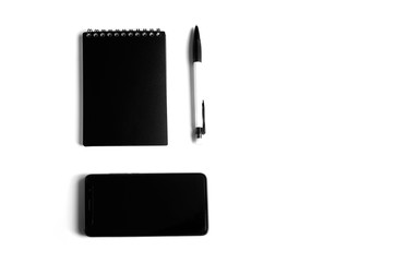 Black and white concept. Business concept with mobile phone, notebook and pen on a white background. Flat lay. Minimalaizm.
