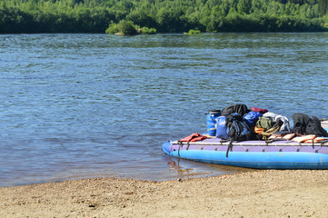 Rafting boat with equipment and bags by the river. Tourism